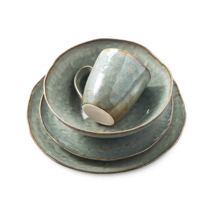 Five-piece moss green dinnerware set stacked together with mug on top, featuring glazed ceramic plates and cup.