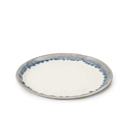Round plate with cream center and blue brushstroke rim pattern on gray stoneware.