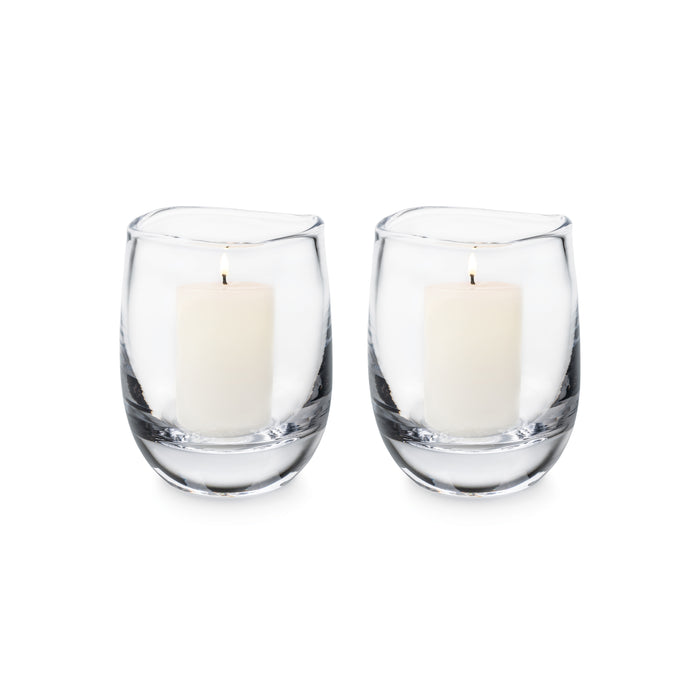 Two clear glass hurricane candleholders with cream-colored pillar candles inside.