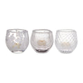 Three frosted glass tealight holders with varied textures containing cream-colored tealight candles.