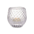 Clear glass tealight holder with textured bubble pattern containing a lit cream-colored candle.
