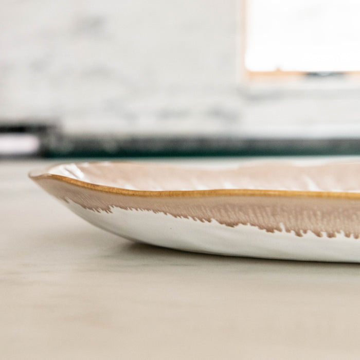 White oval ceramic platter with gold and tan brushstroke design along the rim.