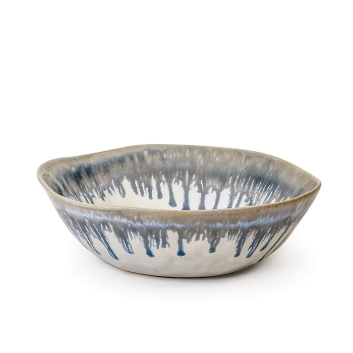 Ceramic bowl with blue and gray drip glaze pattern on cream-colored interior and exterior.
