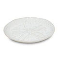 White side plate with sand dollar relief design and beige rim.