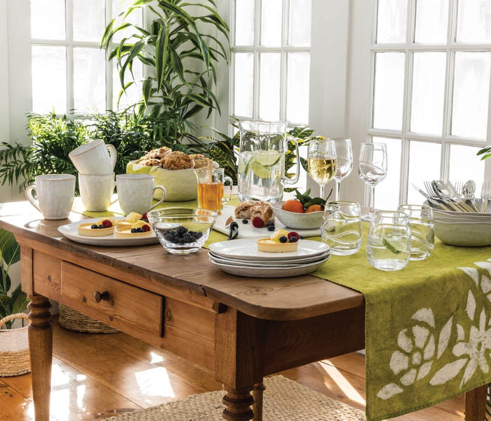 White ceramic serving bowl with textured surface, displayed on dining table with tableware and food.