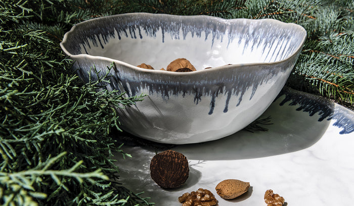 White ceramic serving bowl with blue brush stroke pattern and pouring spout, displayed with nuts.