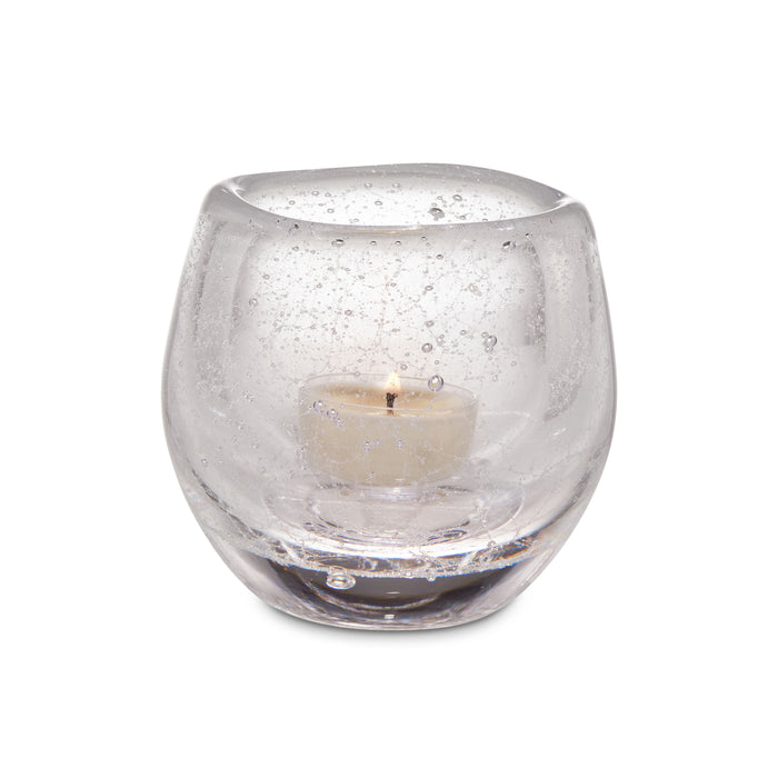 Clear glass tealight holder with cream-colored tealight candle inside.