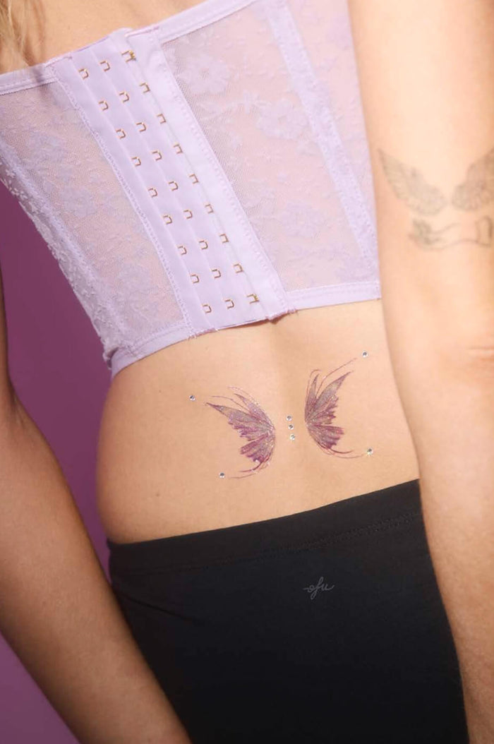Butterfly temporary tattoos with rhinestones on lower back, paired with a lavender corset.