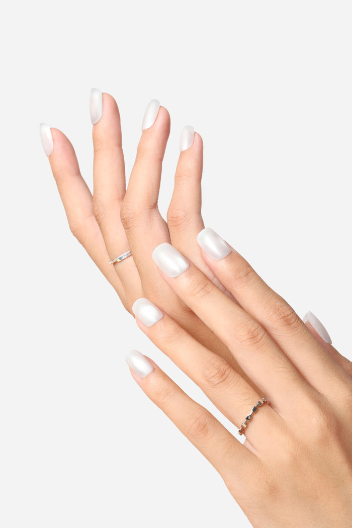 Short square press-on nails in glossy white with pearlescent finish and silver rings.