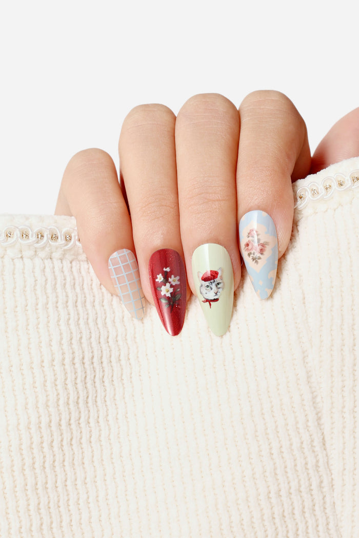 Almond press-on nails featuring a collage of a cat in a beret, floral designs, and a grid pattern.