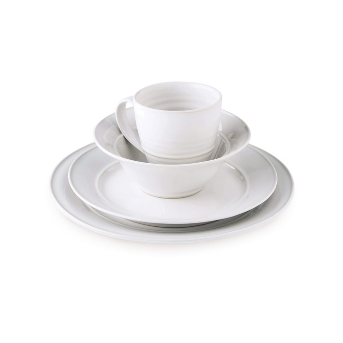 White ceramic dinnerware set stacked with dinner plate, bowl, cup, and saucer.