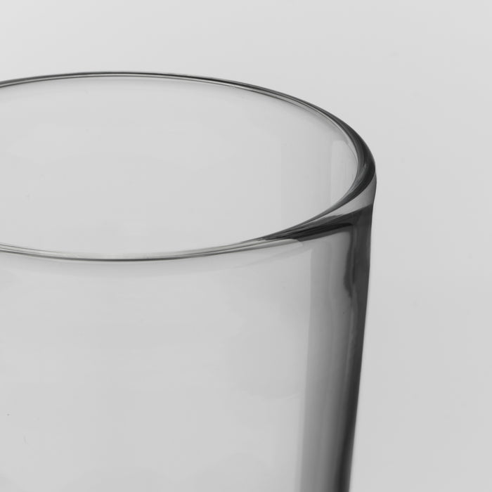 Close-up of a clear glass tumbler with a thick, rounded rim on a light gray background.