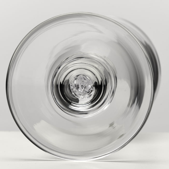 A clear glass stemware glass viewed from the bottom, showing the transparent circular rim and reflective glass center against a light gray background.