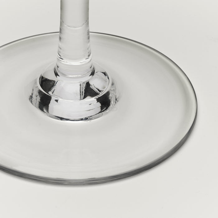 Close-up of a clear glass wine glass base and stem on a light gray background.