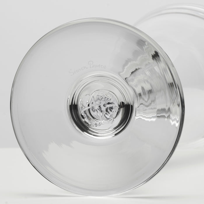 A close-up studio shot of a clear glass and subtle reflections on a light gray background.