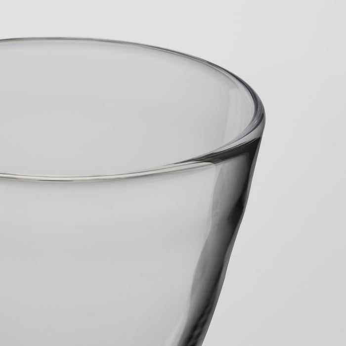 Close-up of a transparent drinking glass with a thick, slightly flared rim, shown against a light gray background.