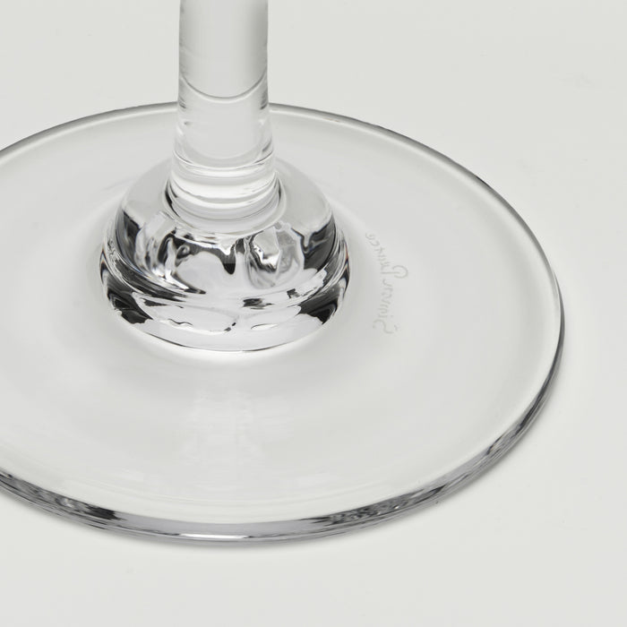 Close-up of a clear glass wine glass base and stem on a light gray background.