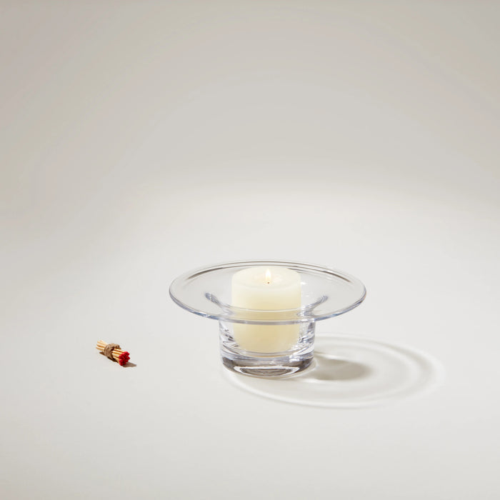 Clear glass hurricane candleholder with wide rim containing a cream-colored pillar candle and a red decorative match.