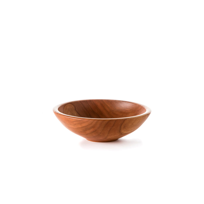 Cherry wood bowl with smooth, curved sides and a light-colored rim on a white background.