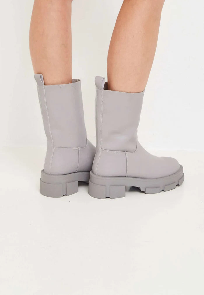 A stylish pair of women's fashion ankle boots in beige, featuring chunky soles and made of leather.