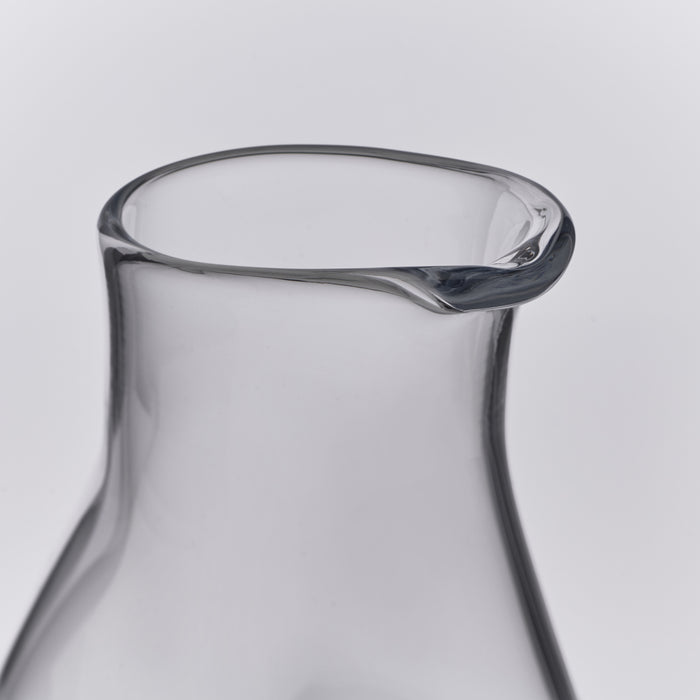 Clear glass carafe with curved sides and a pouring spout at the rim.