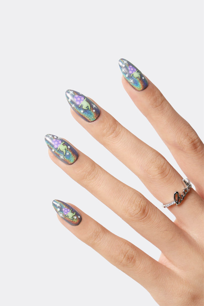 Close-up of holographic press-on nails with a green alien mushroom design, featuring purple polka dots and tiny stars.