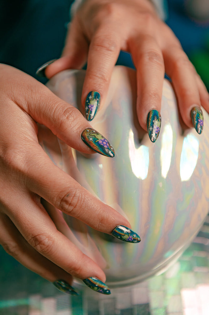 Stiletto press-on nails: dark green with mushroom creatures, stars, and planets. Iridescent sphere background.