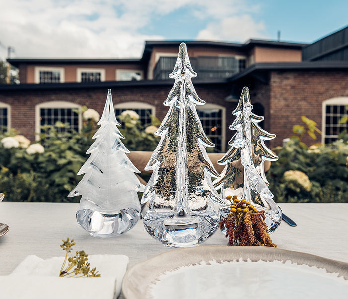 Three clear glass evergreen tree figurines with crackle texture detail, displayed on white surface.