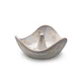 Cream-colored ceramic ring holder with wavy edges and a central cone post, featuring subtle etched details.