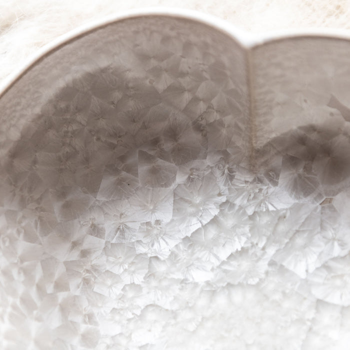 White ceramic heart-shaped bowl with crystalline textured surface and twisted design detail.