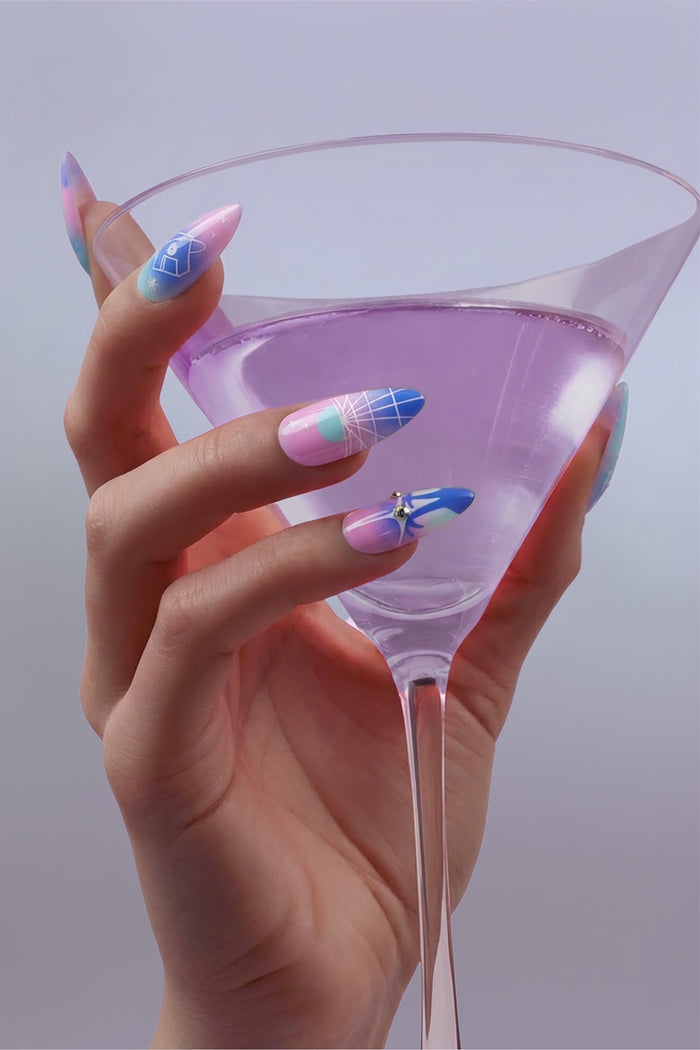 Woman's hand with Cyber Punk press-on nails holding a pink cocktail.