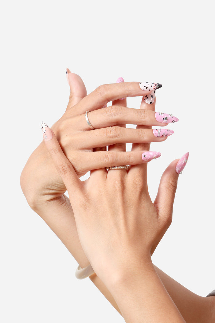 Almond press-on nails with pink and black dalmatian spots, pink base with silver bows and gems.