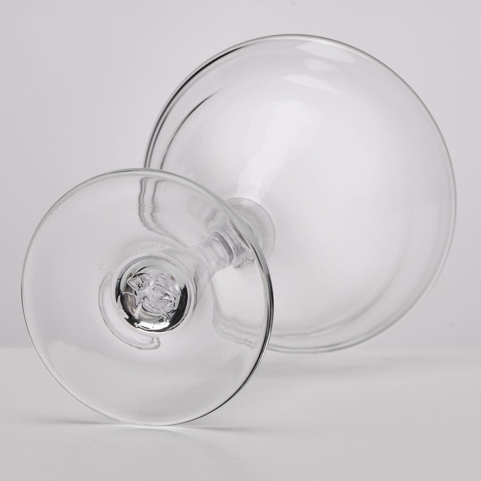 Two clear martini glasses with wide bowls and short stems positioned against a white background.