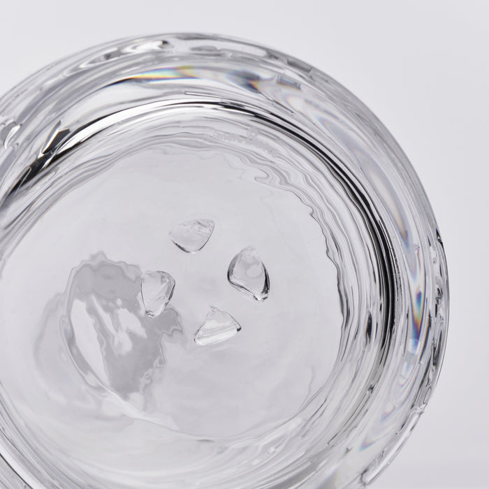 Clear glass decanter with ice cubes and swirled interior design, viewed from above.