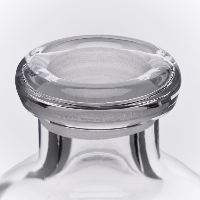 Clear glass decanter with wide bowl opening, rounded rim band, and four short feet on cylindrical base.
