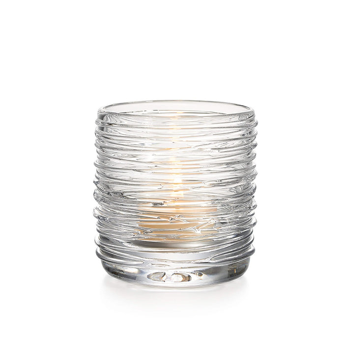 Clear glass tealight holder with horizontal ridged texture and lit candle inside.