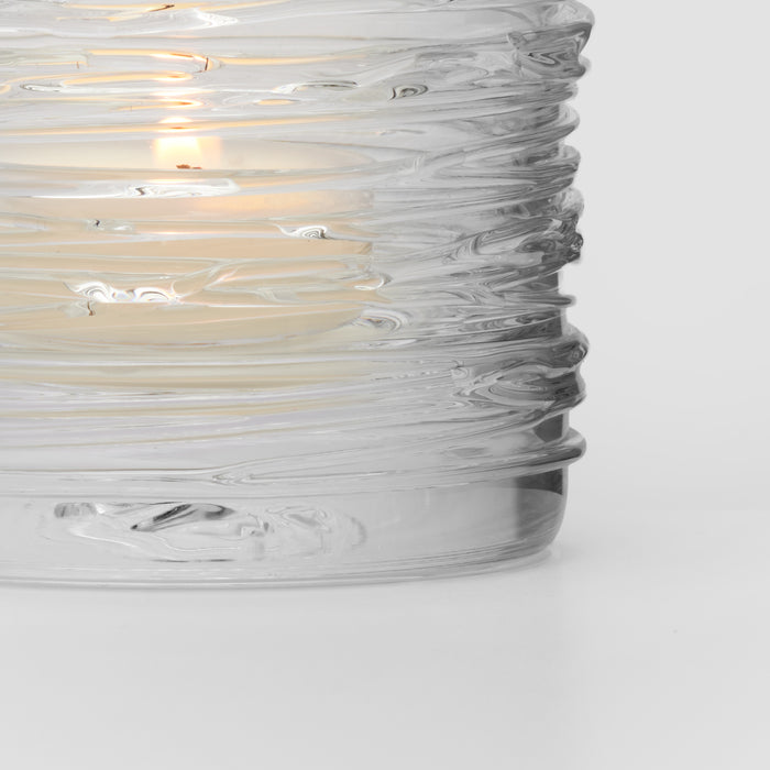 Clear glass tealight holder with textured horizontal ridges and lit candle inside.