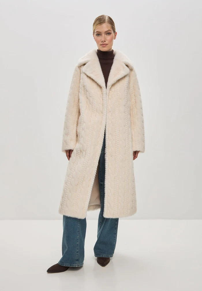 A woman wearing an elegant cream cable knit coat with faux fur trim, a stylish and cozy choice for the winter season.