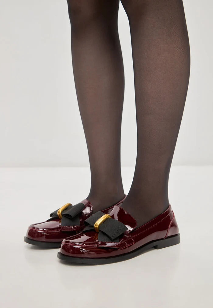 A pair of elegant loafers with black bow detail, also known as Dorothy loafers, featuring a patent red finish, perfect as women's dress shoes.