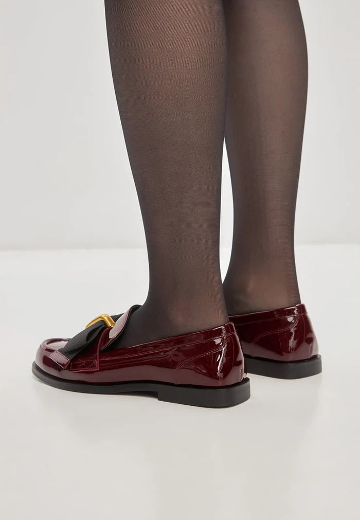 A stylish collection of women's dress shoes, including elegant loafers, black bow loafers, Dorothy loafers, and patent red shoes displayed on a white background.