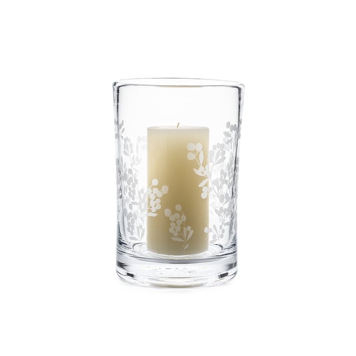 Clear glass hurricane with white berry branch engravings holding a cream-colored pillar candle.