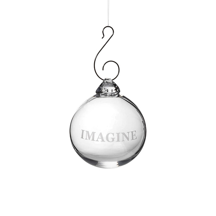 Clear glass round ornament engraved with "IMAGINE" text, suspended from a curved metal hook.