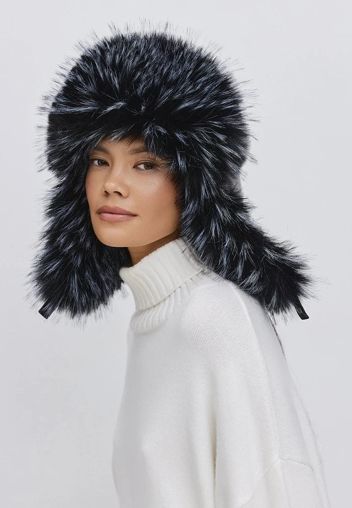 A woman models a stylish blue faux fur hat, perfect for winter wear, with long ear flaps for added warmth and flair.