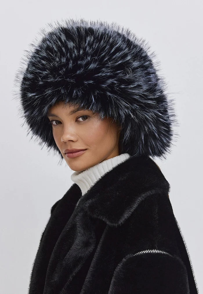 A woman wearing a stylish blue faux fur hat paired with a cozy white turtleneck, ideal for winter fashion.