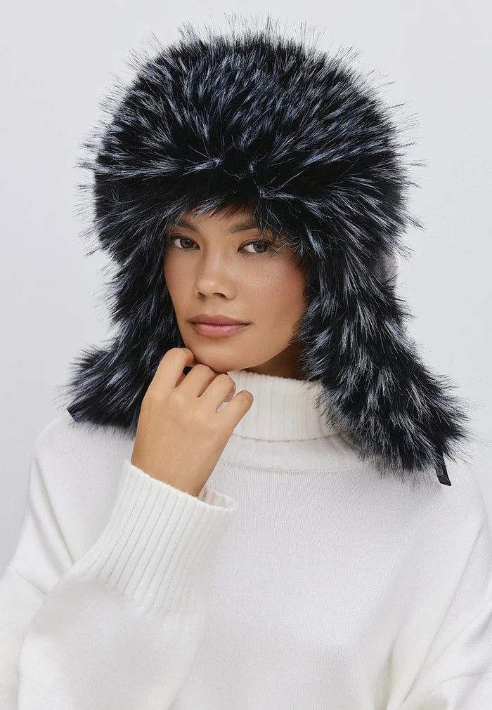 Woman wearing a stylish blue faux fur hat, perfect for winter, paired with a cozy white sweater.