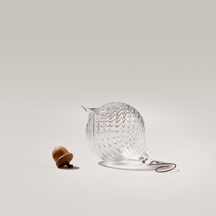Clear glass finial ornament with optic ridged pattern and metal cap, shown next to walnut for scale.