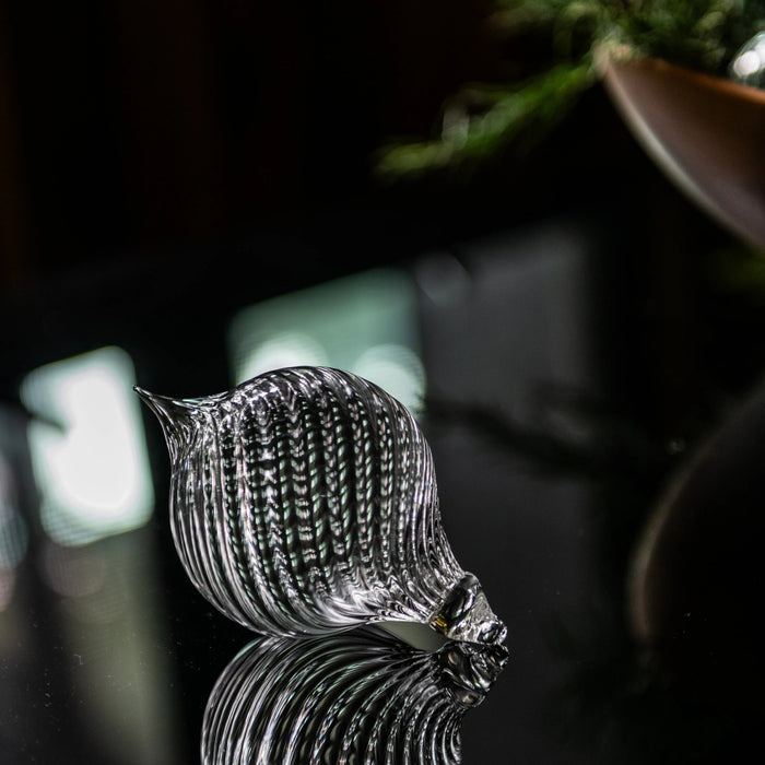 Clear glass finial ornament with ribbed texture and pointed top, displayed against dark background.