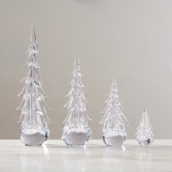 Four clear glass evergreen trees in graduated sizes with pointed tops and faceted branches, displayed in a row.