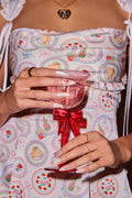 Almond press-on nails with floral and strawberry designs, held by hands wearing gold rings.