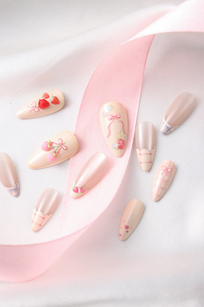 Floral Femme almond press-on nails with pink bows, strawberries, and floral accents.